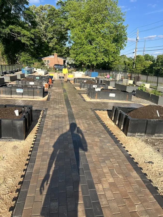 Long paver walkway through a community garden