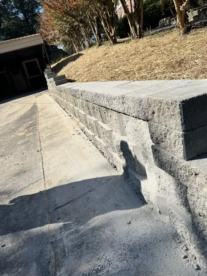 Block retaining wall holding a slope beside a driveway