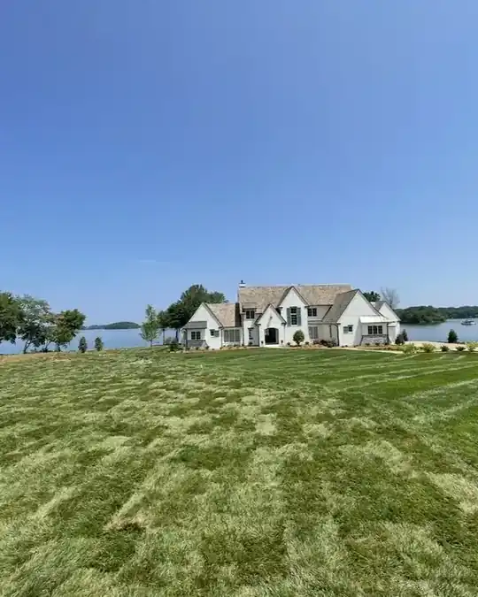 Big green lawn by a lake house