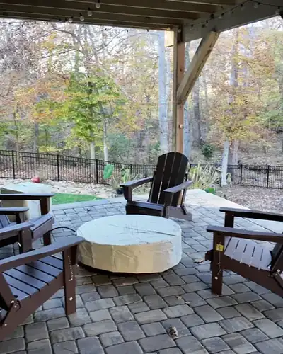 Paver patio under a deck with a fire table and chairs