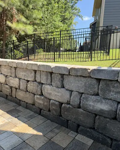 Paver patio below a natural stone wall
