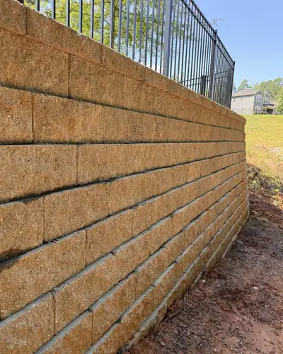 Tall block retaining wall with a fence on top